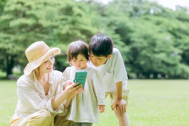 外でスマホを見る親子